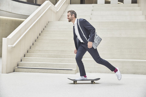 Geschäftsmann fährt Skateboard im Treppenhaus, lizenzfreies Stockfoto