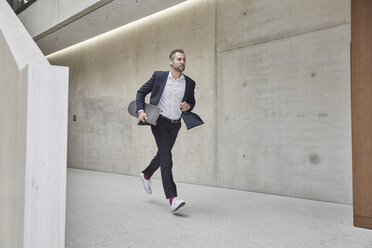 Geschäftsmann läuft mit Skateboard an Betonwand entlang - FMKF002947