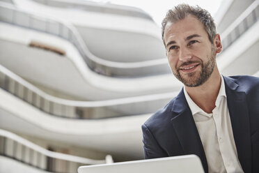 Smiling businessman in office building - FMKF002953