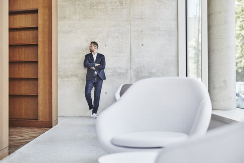 Businesssman leaning against concrete wall - FMKF002955