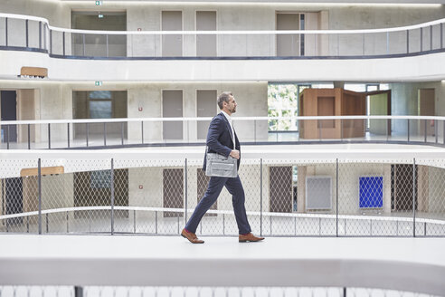 Geschäftsmann zu Fuß mit Tasche in einem modernen Bürogebäude - FMKF002961