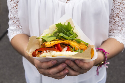 Hands of teenage girl holding corn flat bread stuffed with vegetables - EVGF003070