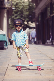 Portrait of little boy with skateboard wearing oversized sunglasses and basecap - XCF000096