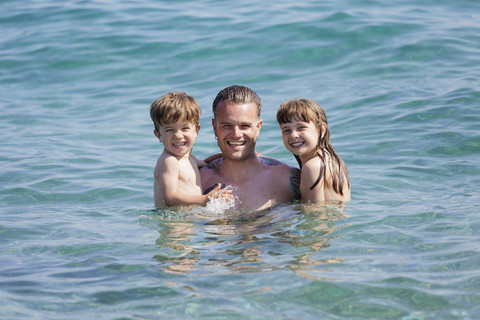 Tattooed man with his children in the sea stock photo