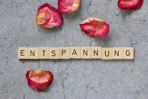 Rose petals and Scrabble tokens forming the word 'Entspannung' stock photo