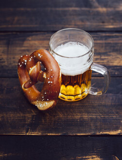 Brezel und Glas Bier auf dunklem Holz - PPXF000024