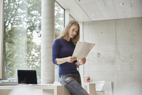 Junge Frau sieht sich Dokumente an, lizenzfreies Stockfoto