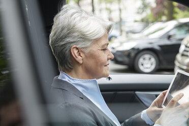 Porträt einer Geschäftsfrau, die in einem Auto sitzt und ein Tablet benutzt - FMKF003036