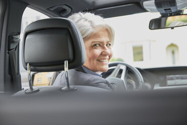 Porträt einer lächelnden Geschäftsfrau, die in einem Auto sitzt - FMKF003037