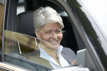 Porträt einer lächelnden Geschäftsfrau mit Tablet, die in einem Auto sitzt - FMKF003039