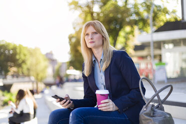 Blonde Geschäftsfrau mit Coffee to go und Smartphone schaut in die Ferne - NAF000016