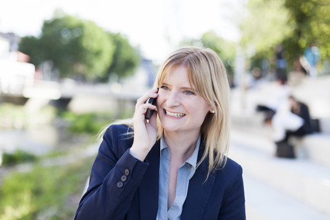 Porträt einer lächelnden blonden Geschäftsfrau am Telefon, lizenzfreies Stockfoto