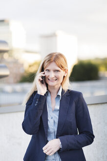Porträt einer lächelnden blonden Geschäftsfrau am Telefon - NAF000038