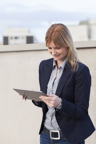 Lächelnde Geschäftsfrau mit Blick auf ein Tablet, lizenzfreies Stockfoto