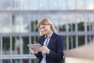 Smiling businesswoman looking at tablet - NAF000058