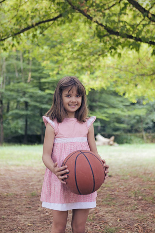 Smiling little girl with basketball wearing pink dress stock photo
