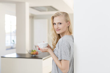 Lächelnde blonde Frau mit einer Tasse Kaffee in der Küche - SHKF000646