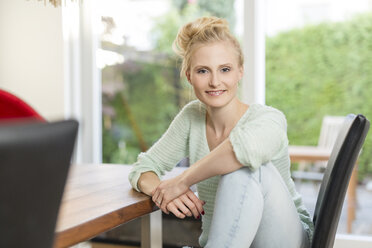 Portrait of smiling blond woman sitting at dining table - SHKF000661