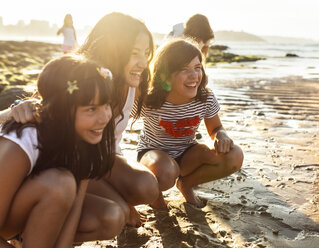 Drei glückliche Mädchen am Strand bei Sonnenuntergang - MGOF002265