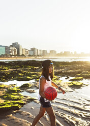 Mädchen spielt mit einem Ball am Strand bei Sonnenuntergang - MGOF002275