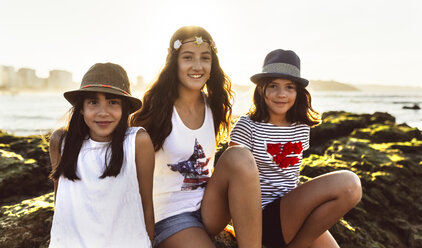 Drei lächelnde Mädchen am Strand bei Sonnenuntergang - MGOF002276