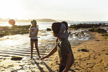 Kinder spielen mit einem Ball am Strand bei Sonnenuntergang - MGOF002279