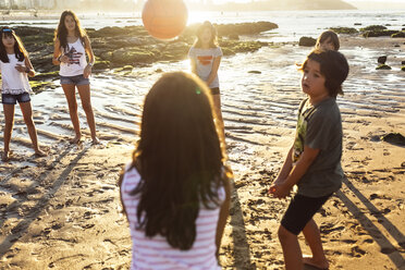 Kinder spielen mit einem Ball am Strand bei Sonnenuntergang - MGOF002280