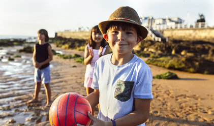 Porträt eines Jungen mit einem Ball am Strand bei Sonnenuntergang - MGOF002289