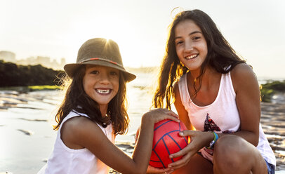 Two happy girls with ball on the beach at sunset - MGOF002294