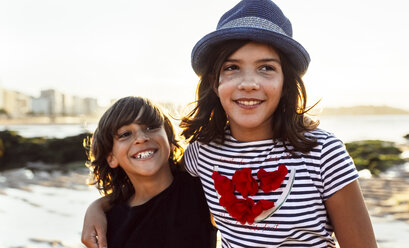 Two kids embracing on the beach at sunset - MGOF002295