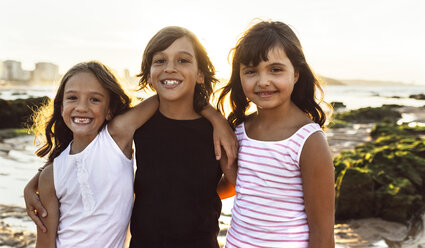 Portrait of three happy kids on the beach at sunset - MGOF002296