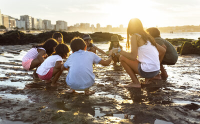 Kids playing hand in hand on the beach at sunset - MGOF002300