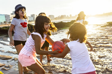 Kinder spielen mit einem Ball am Strand bei Sonnenuntergang - MGOF002303