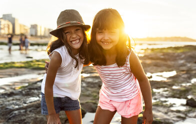 Portrait of two smiling girls on the beach at sunset - MGOF002309