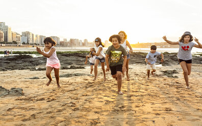 Kinder laufen bei Sonnenuntergang am Strand - MGOF002315