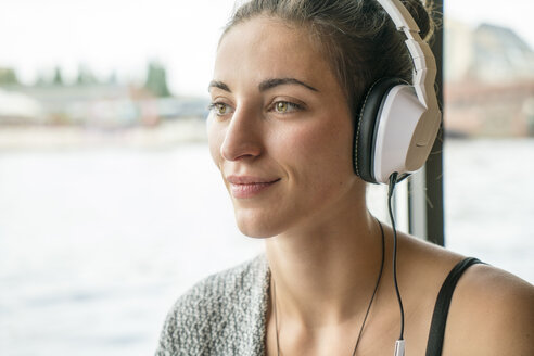 Porträt einer entspannten Frau, die mit Kopfhörern Musik hört - TAMF000569