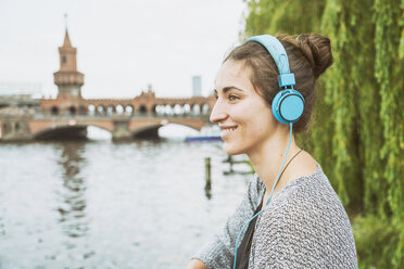 Deutschland, Berlin, entspannte Frau hört Musik mit Kopfhörern - TAMF000572