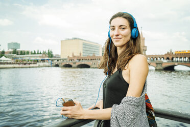 Deutschland, Berlin, Porträt einer entspannten Frau, die mit Kopfhörern Musik hört - TAMF000575