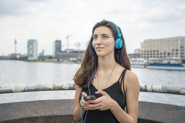 Germany, Berlin, relaxed woman listening music with headphones - TAMF000576