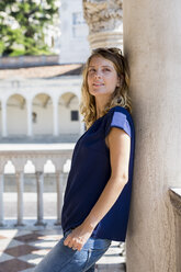 Italy, Udine, blond tourist leaning against column watching something - MAUF000841