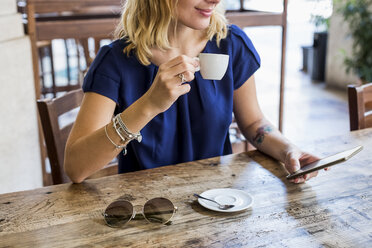 Frau trinkt Espresso in einem Straßencafé und schaut auf ihr Handy, Teilansicht - MAUF000846