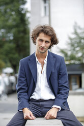 Portrait of serious young man sitting on a wall - TAMF000587