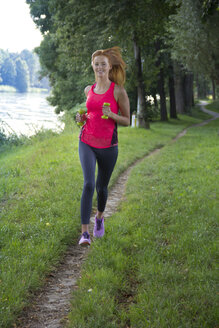 Junge Frau joggt mit Hanteln - YFF000565