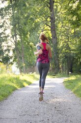 Junge Frau joggt mit Hanteln - YFF000568