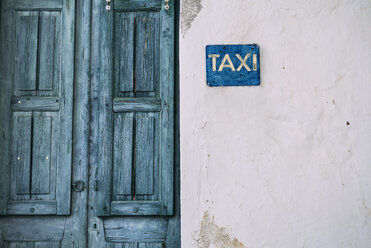 Griechenland, Kykladen, blaue Holztür und Taxischild an der Fassade - GEMF000985