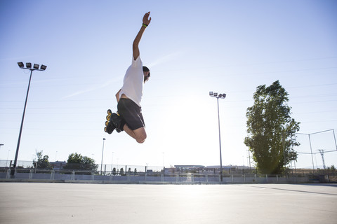 Mann mit Rollschuhen springt beim Skaten, lizenzfreies Stockfoto