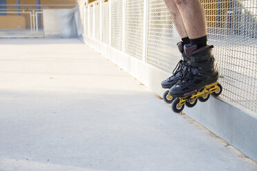 Beine eines Mannes mit Rollschuhen auf einem Geländer - ABZF001017