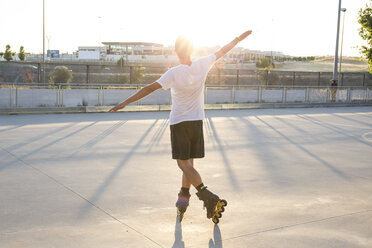 Man with rollerblades and arms extended at sunset - ABZF001029