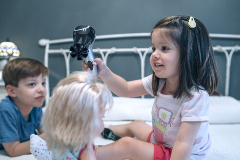 Mädchen föhnt die Haare einer Puppe, die von ihrem Bruder beobachtet wird - DAPF000310