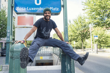 Young single in Berlin-Mitte, in front of underground sign Rosa-Luxemburg-Platz - TAMF000590